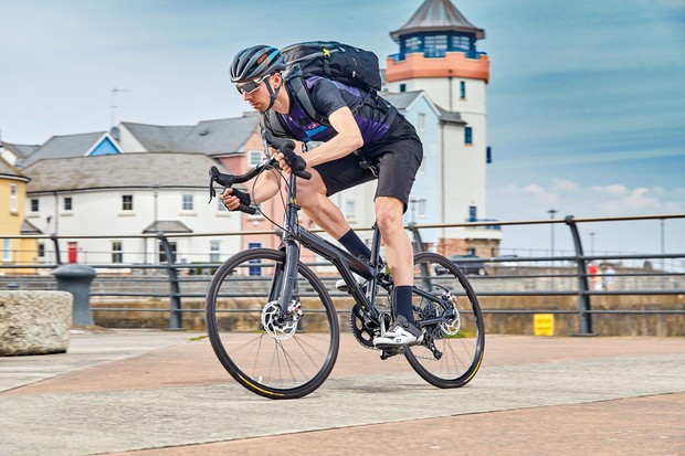 A male cycling on a blue bicycle on the harbour-side